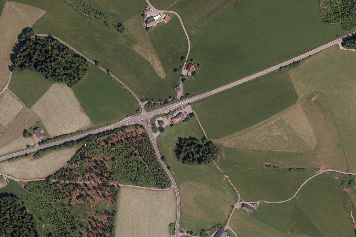 Luftbild der Umgebung: das Gasthaus Schweizerhof an der Abzweigung der Jostalstraße, ringsum Wiesen und Wald