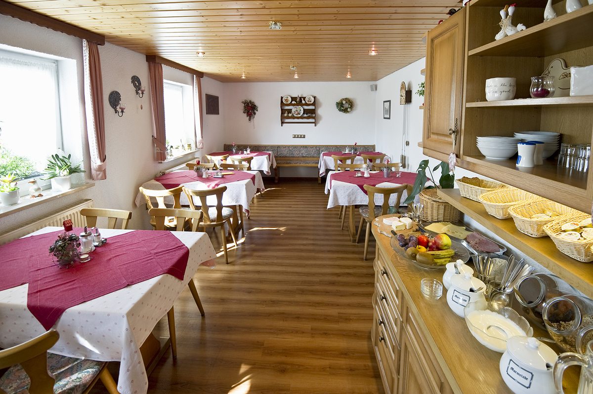 Frühstücksbuffet mit Geschirr und Körben neben den gedeckten Tischen