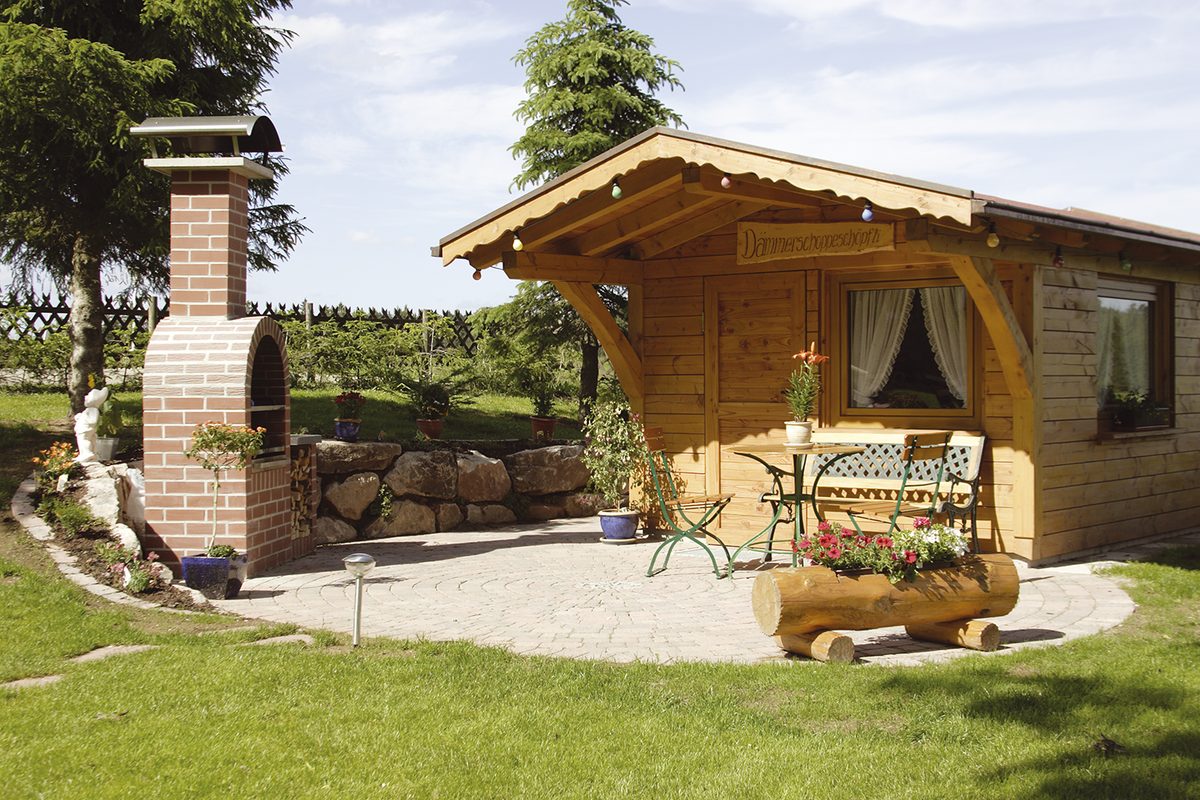 Der hölzerne Gartenpavillon im Garten des Gasthauses, daneben ein gemauerter Grill