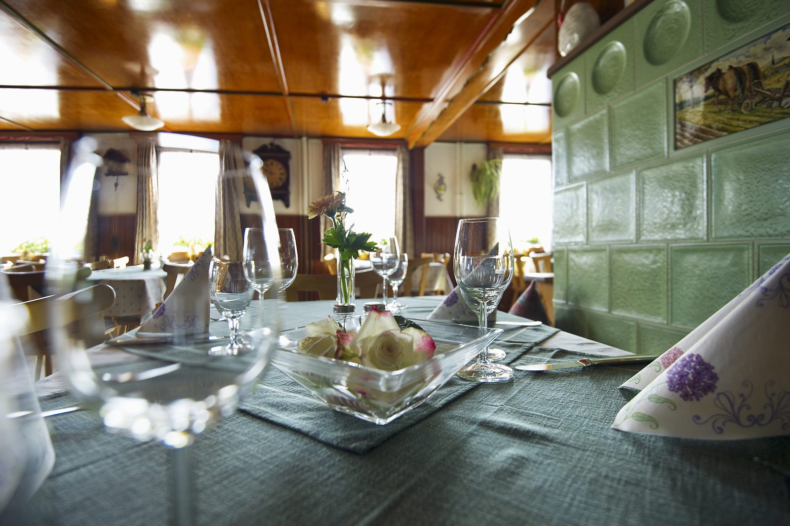 Gedeckter Tisch in der Gaststube vor dem grünen Kachelofen